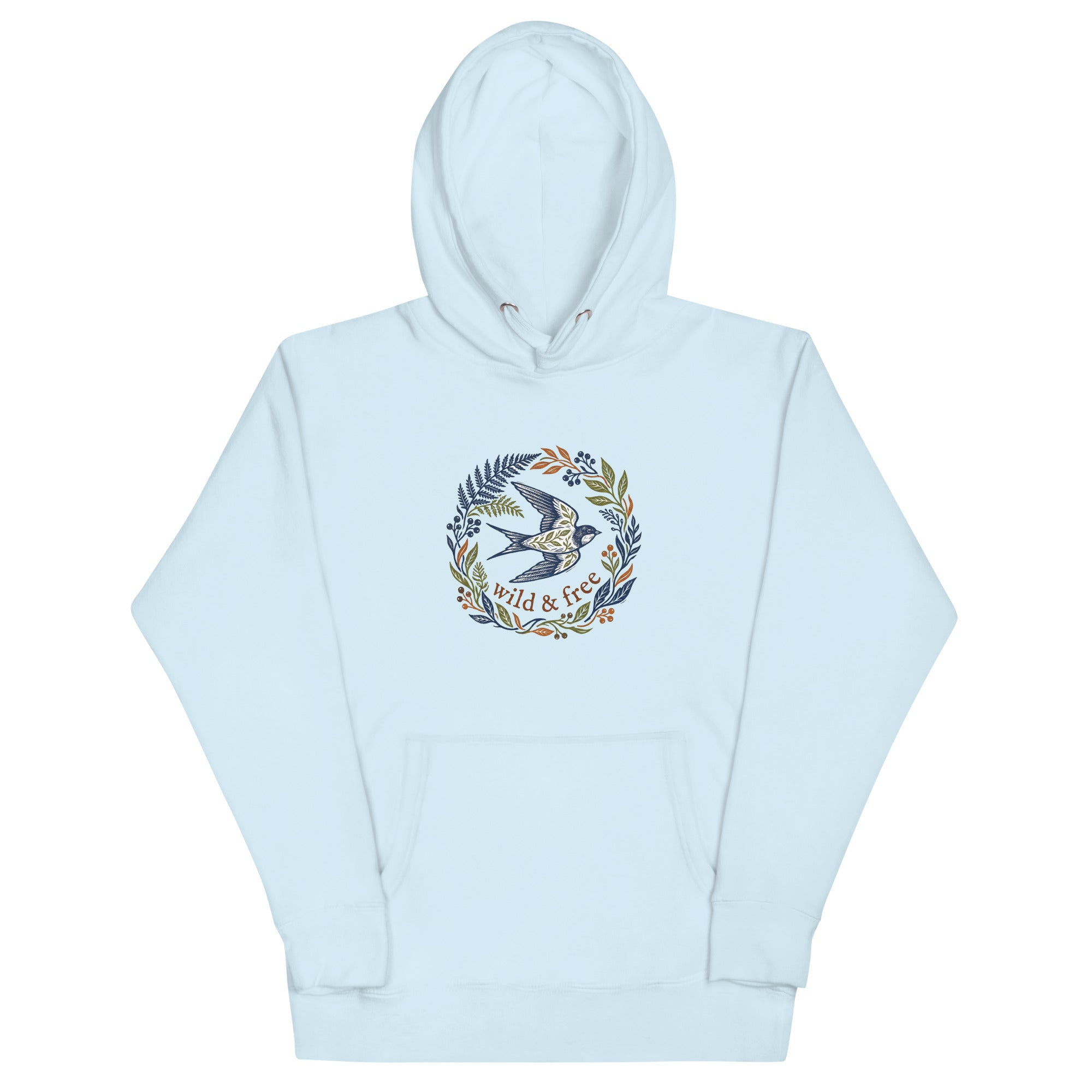 A light sky-blue pullover hoodie laid flat against a white background. The front features a central graphic design of a stylized flying swallow surrounded by a wreath of ferns, leaves, and berries in navy, olive, and rust colors. Below the bird, the text "wild & free" is written in a brown serif font.