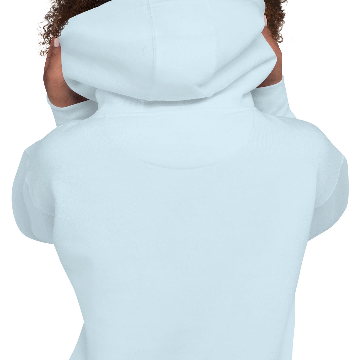 The back view of a person wearing the sky-blue hoodie. The model has dark curly hair and is holding the sides of the hood. The image highlights the plain back of the garment and the stitching details on the hood construction.