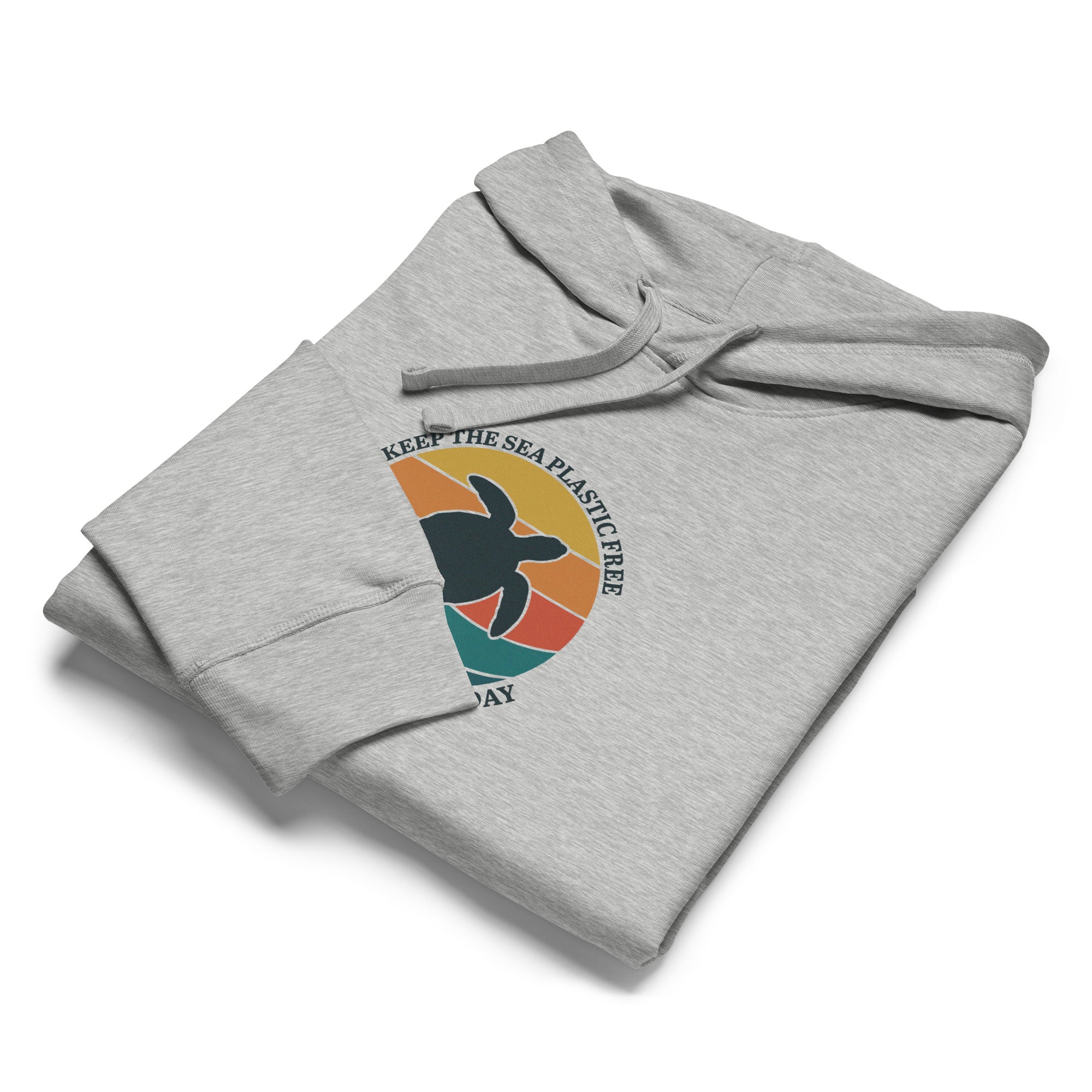 An angled, close-up shot of the heather grey hoodie folded neatly on a white surface. The focus is on the circular "Keep the sea plastic free" graphic and the soft texture of the organic fabric.