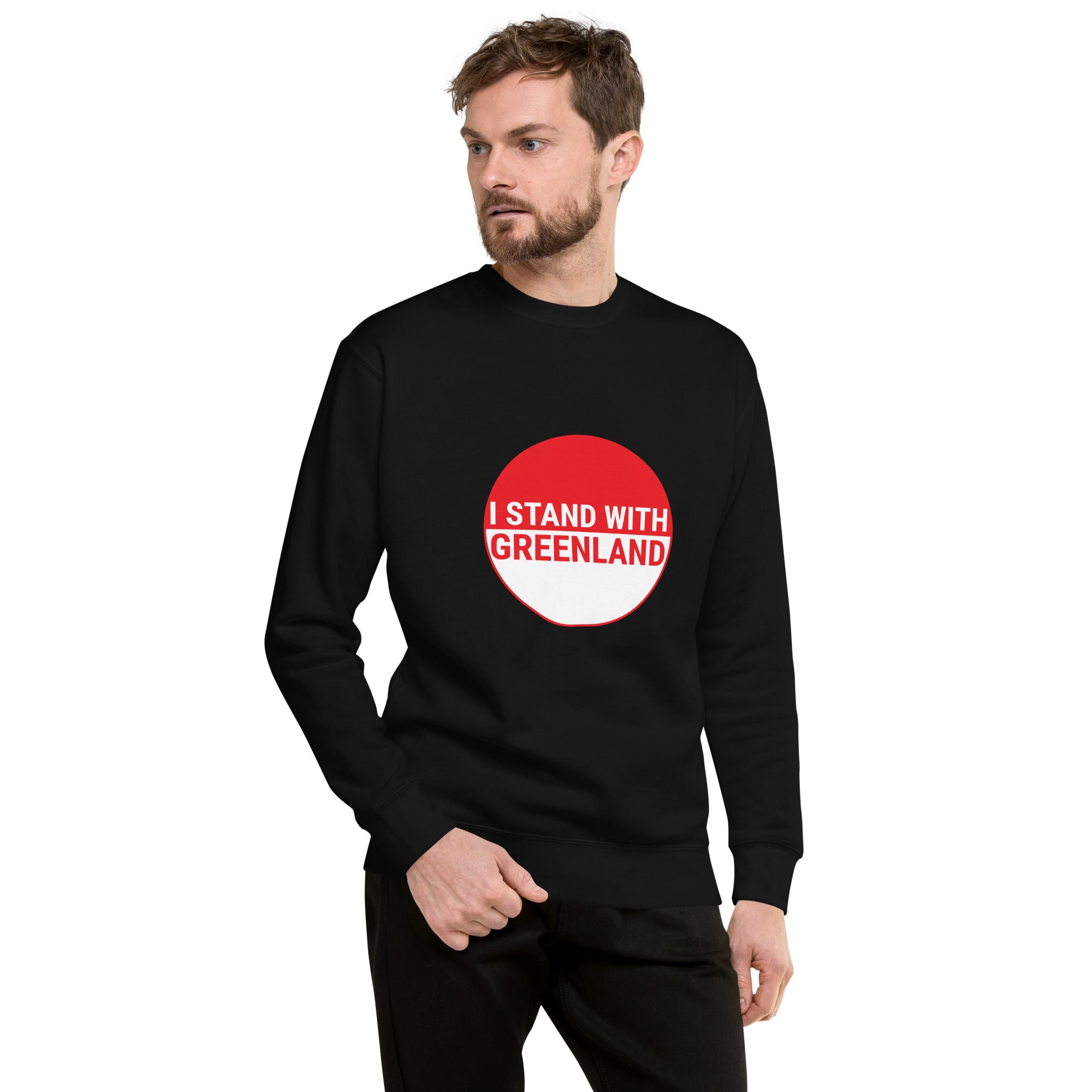 A man looking off-camera while wearing a black sweatshirt with a large red and white circular graphic containing the text "I STAND WITH GREENLAND."