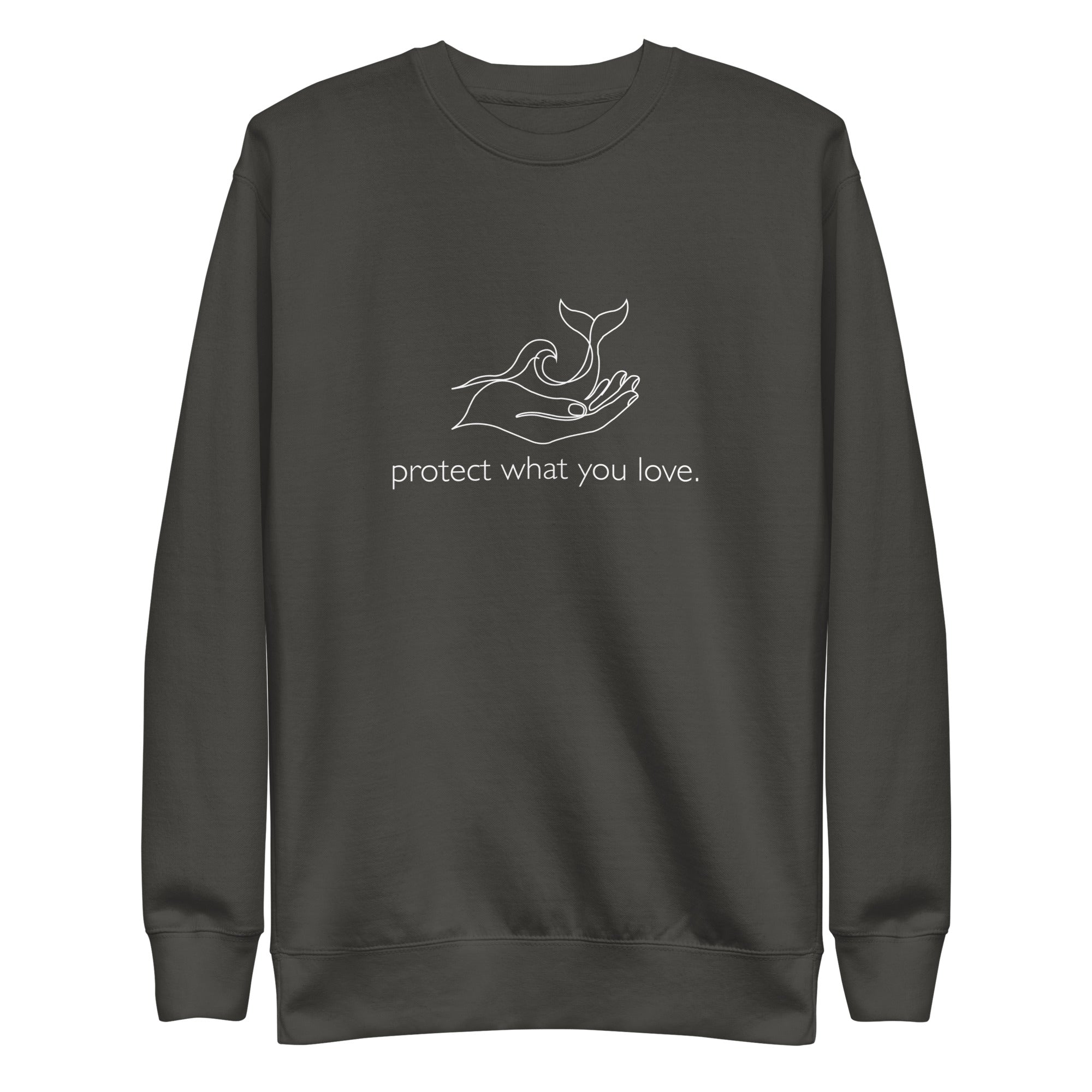 A high-resolution front view of a vintage black organic crewneck sweatshirt. Centered on the chest is a minimalist white line art graphic of a hand cradling a whale's tail and an ocean wave, with the lowercase phrase "protect what you love." printed beneath it.
