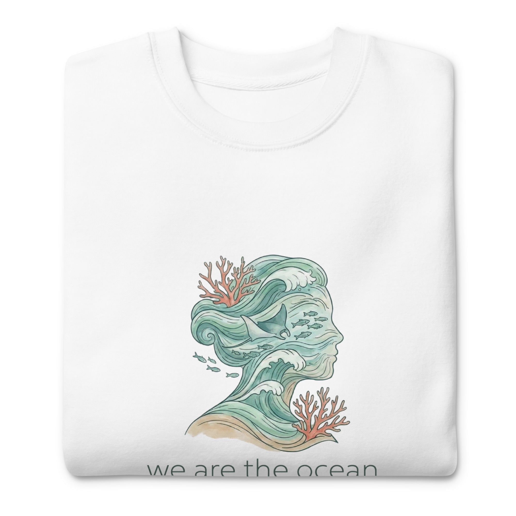 A close-up, angled shot of the white hoodie folded neatly on a white surface, focusing on the details of the waves and marine life within the profile silhouette and the soft texture of the fabric.